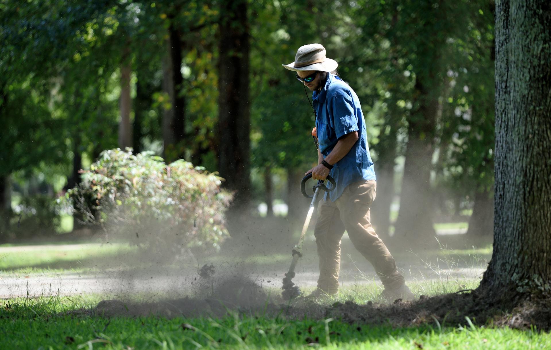 Confident landscape business owner with crew working on a job site in the background